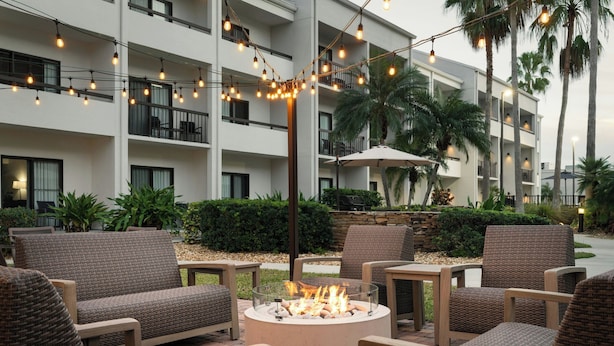 Un patio con mobiliario exterior, una fogata y luces colgantes.