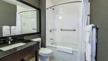 Un baño moderno con lavamanos de superficie negra, inodoro blanco, ducha con cerramiento de vidrio y un espejo grande.