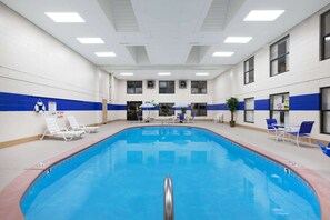 A large indoor swimming pool with clear water, surrounded by lounge chairs and a few potted plants. - Super 8 by Wyndham Jacksonville AR (Jacksonville)
