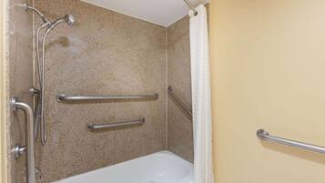 Ein Badezimmer mit Badewanne, Haltegriffen und Duschkopf.