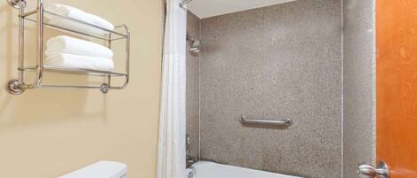 A bathroom with a shower, a toilet, and a towel rack with towels.