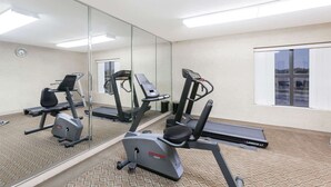 A gym with cardio machines, a mirror, and a window with a view. - Super 8 by Wyndham Jacksonville AR (Jacksonville)