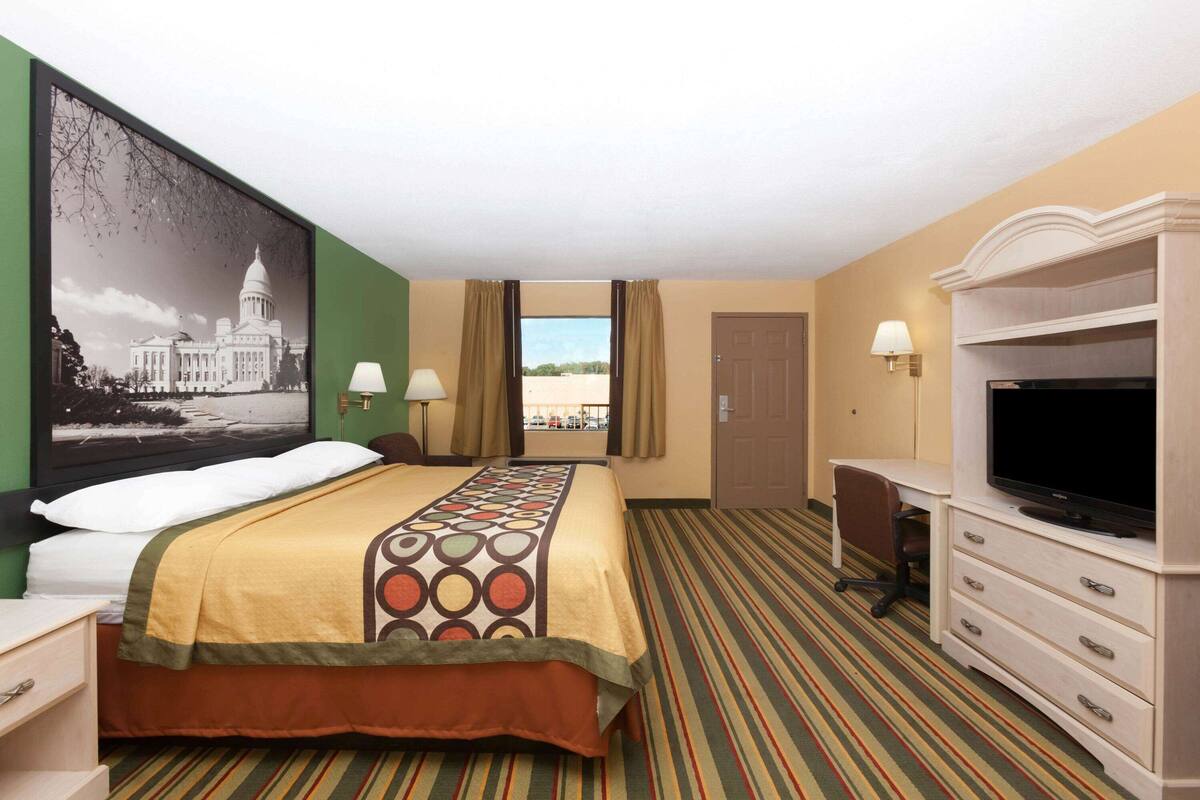 Ein Hotelzimmer mit Bett, Fernseher, Schreibtisch und Blick auf den Strand.