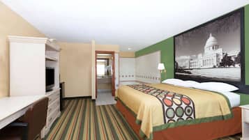 A hotel room with a bed, a desk, a chair, and a large wall-mounted picture of a government building.