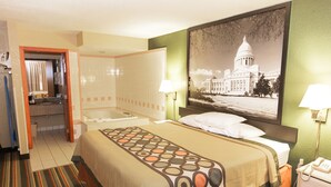 A hotel room with a large bed, a bathroom, a shower, and a view of a building. - Super 8 by Wyndham Jacksonville AR (Jacksonville)