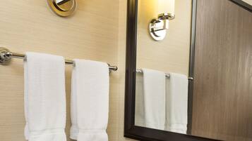 A bathroom with a granite countertop, a white sink, two wall-mounted towel racks, a mirror, and two wall sconces.