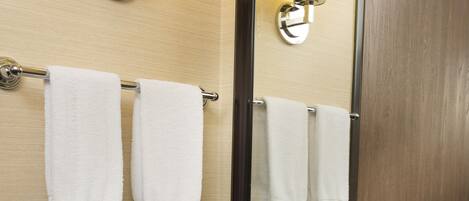 A bathroom with a granite countertop, a white sink, two wall-mounted towel racks, a mirror, and two wall sconces.