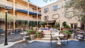 A courtyard with outdoor seating, a fountain, and potted plants.