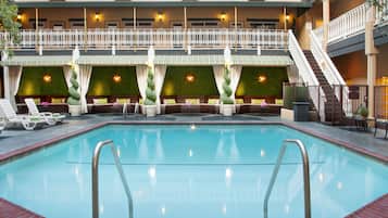 A pool area with lounge chairs and a seating area with a view of the building's exterior.
