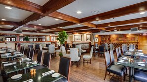 A restaurant with wooden beams, marble tables, and leather booths.
