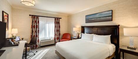 A hotel room with a large bed, a desk with a chair, a TV, and a painting on the wall.