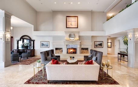 A spacious living room with a fireplace, comfortable seating, and a high ceiling.