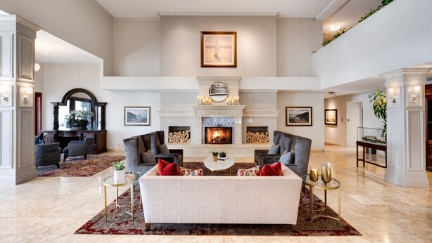 A spacious living room with a fireplace, comfortable seating, and a high ceiling.
