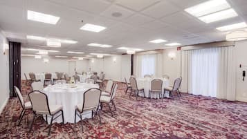 Une salle de conférence équipée de tables rondes, de chaises et d’un sol recouvert de moquette.