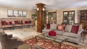 A spacious living room with a patterned sofa, a glass coffee table, and a red floral centerpiece.