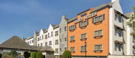 Un hotel con un cartel que dice "AYRES SUITES", de diseño arquitectónico moderno, con múltiples ventanales y fachada de piedra.