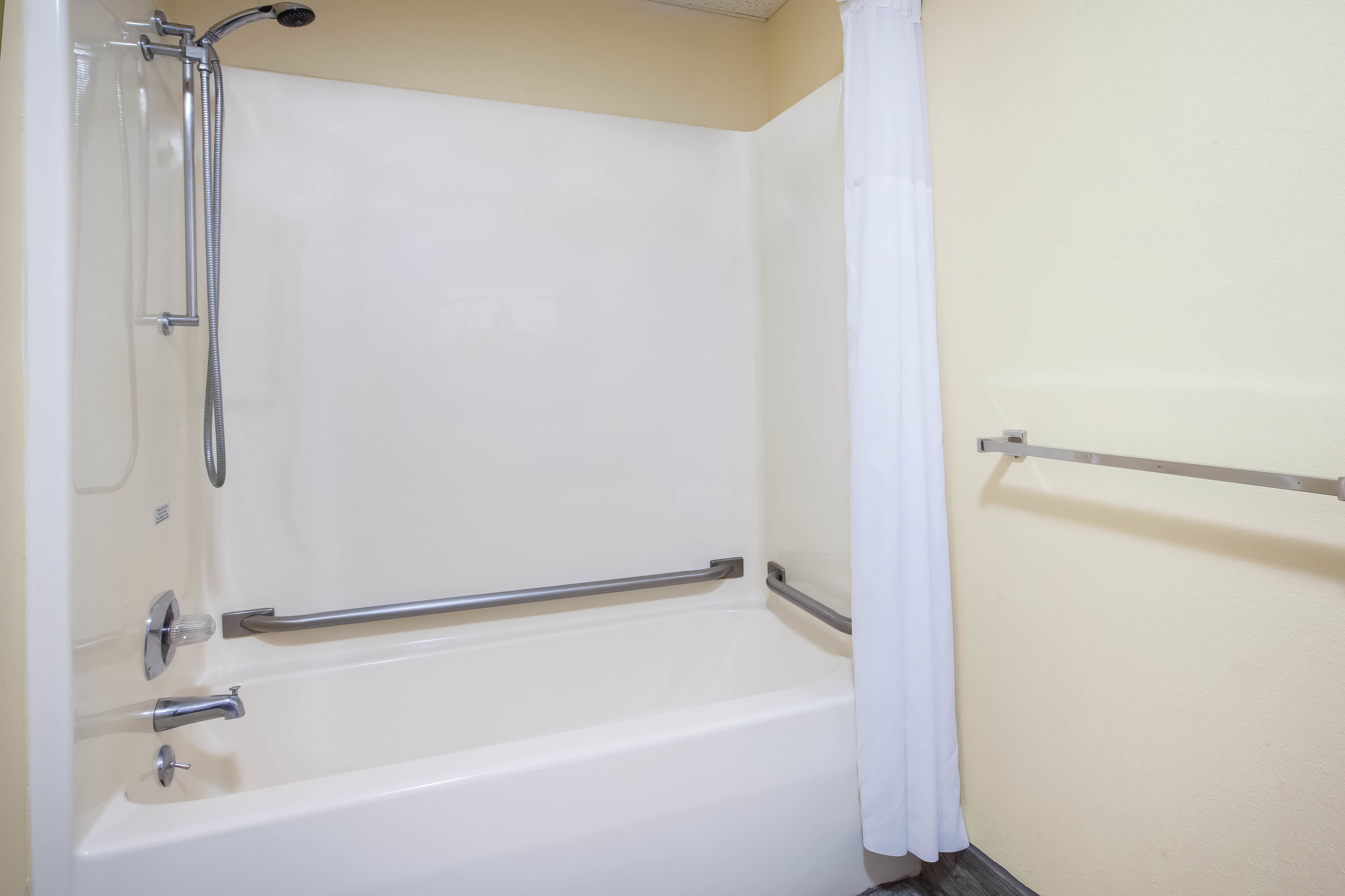 A white bathtub with a showerhead and grab bars.