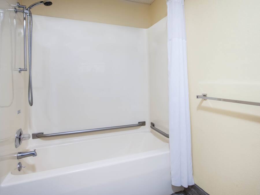 A white bathtub with a showerhead and grab bars.