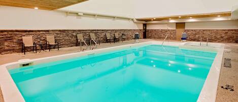 A large indoor swimming pool with a stone wall and wooden ceiling.