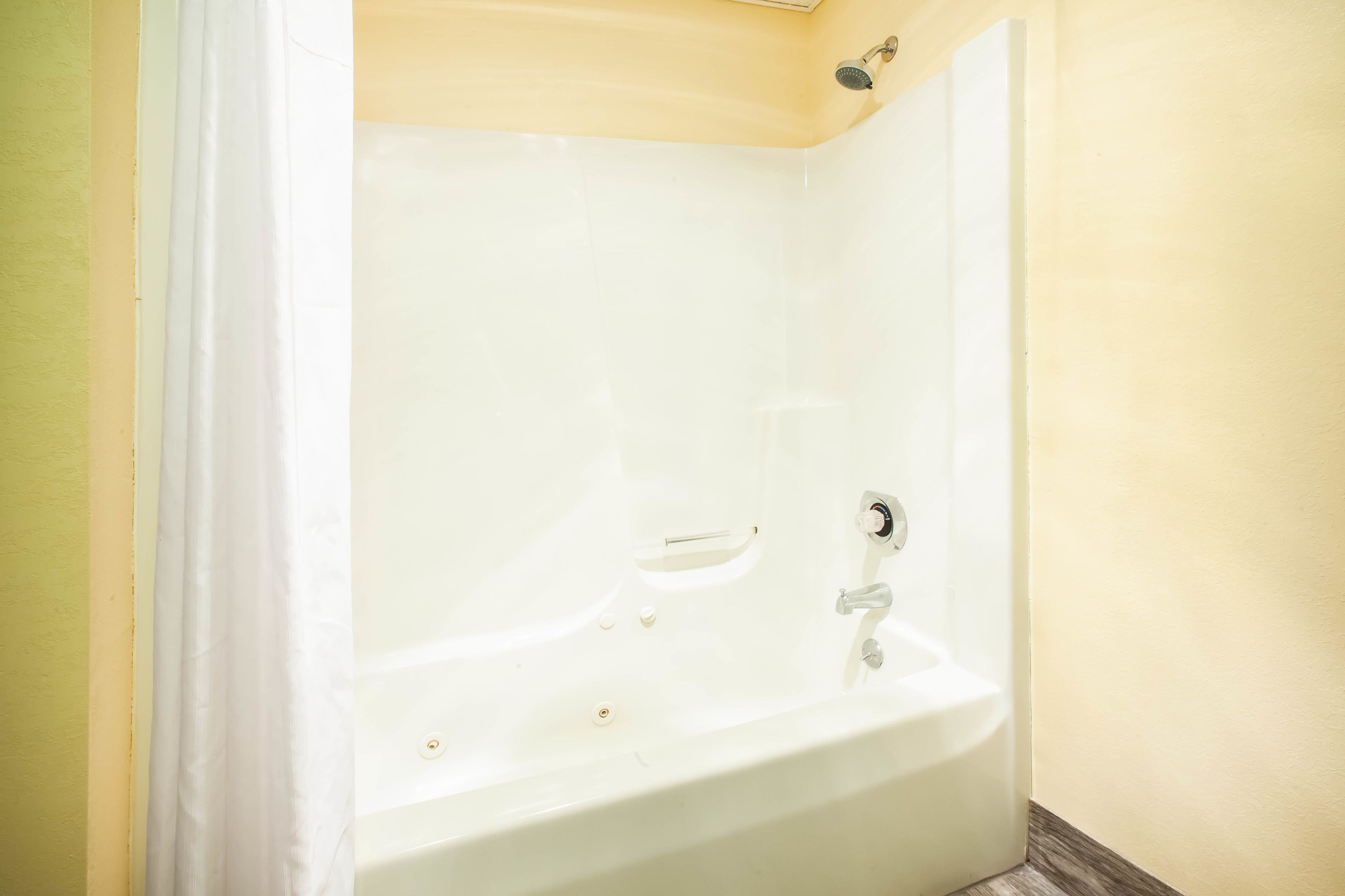 Una bañera blanca en un baño con paredes amarillas y suelo de madera.