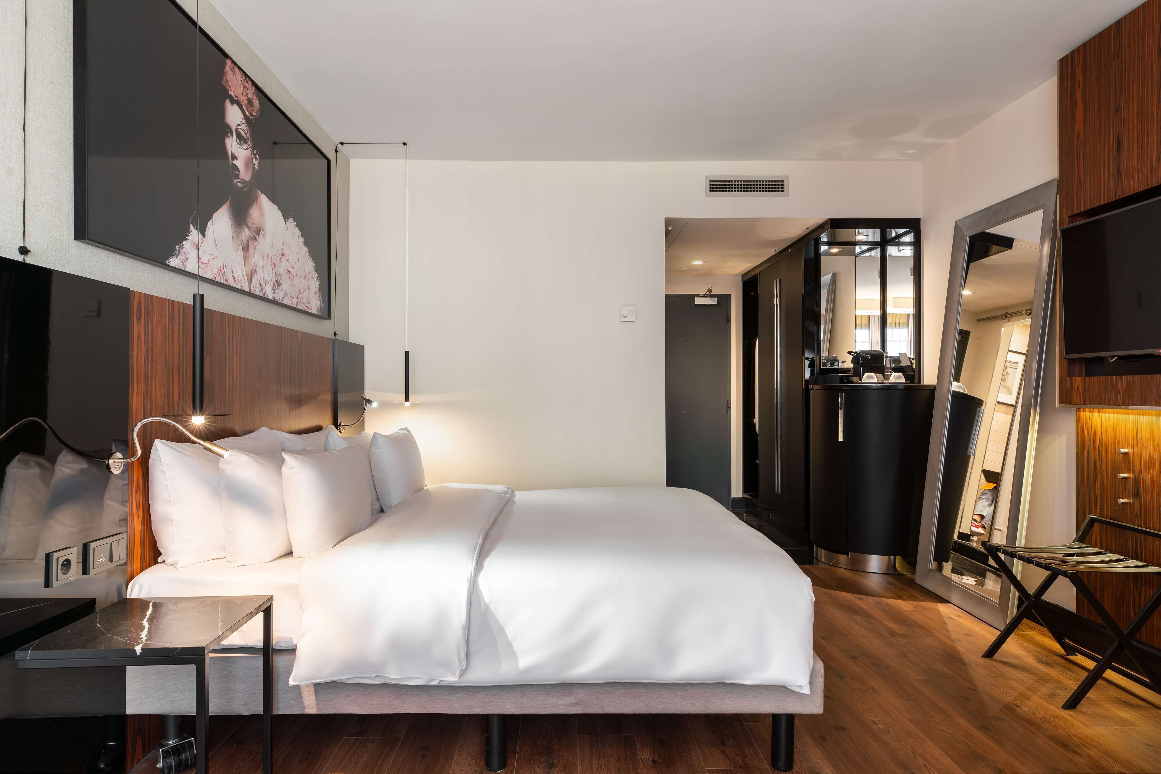 A modern hotel room with a large bed, a desk, and a flat-screen TV.