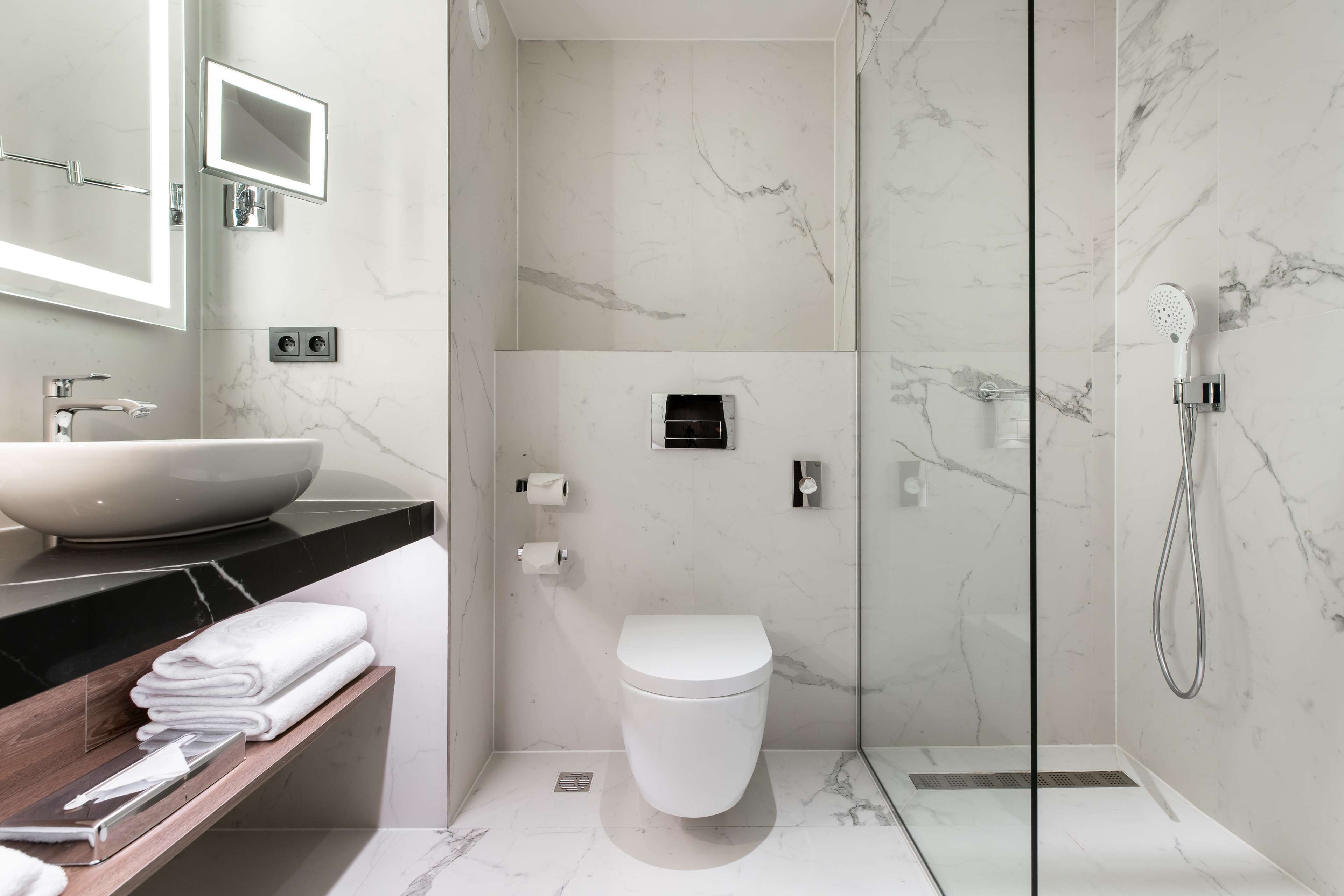 Een moderne badkamer met een groot wastafel, een toilet en een douche met glazen wanden.