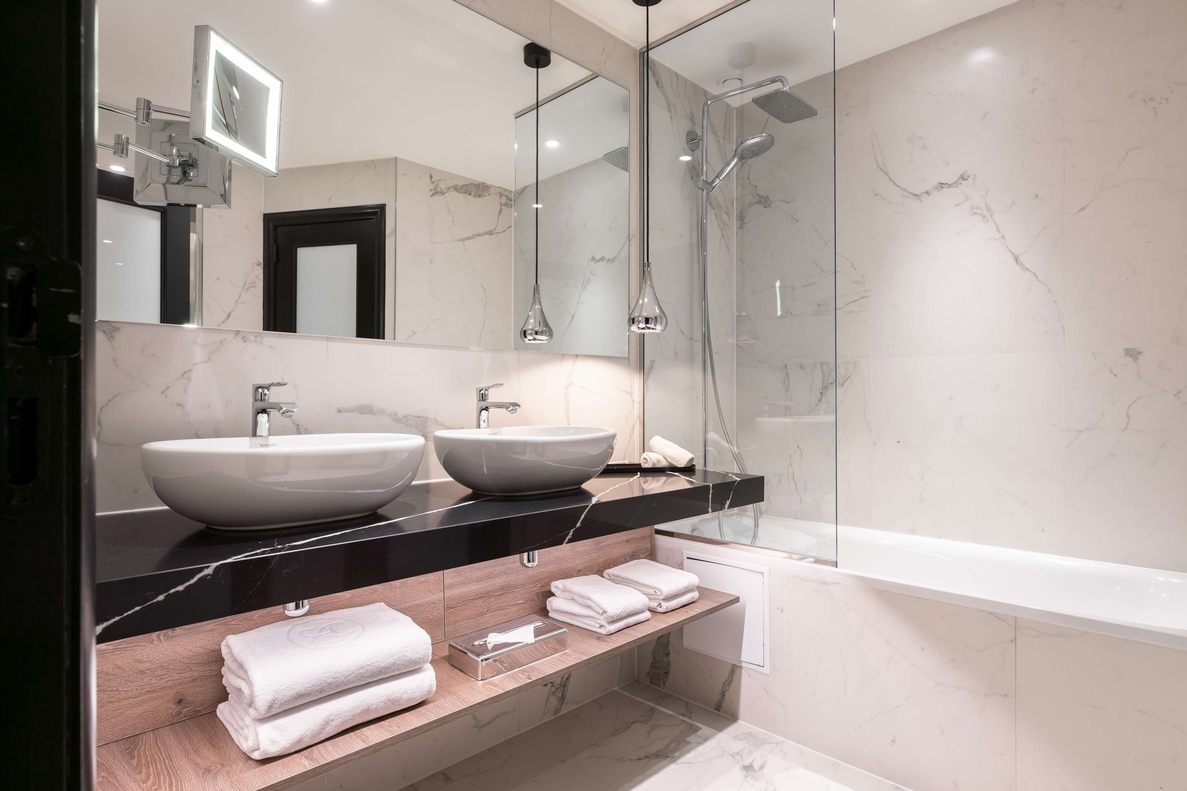 A modern bathroom with two vessel sinks, a large mirror, and a glass-enclosed shower.