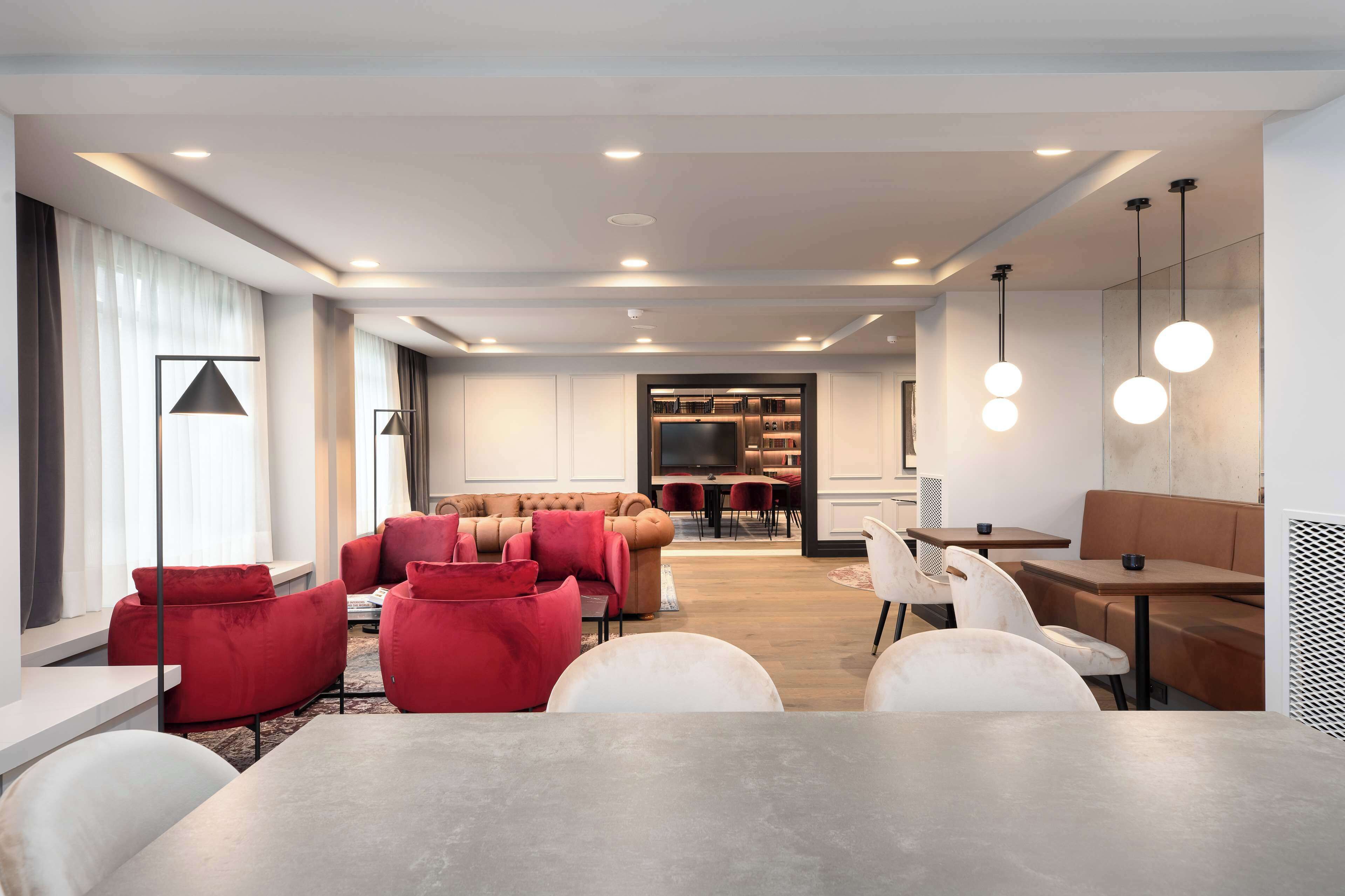 Een moderne woonkamer met een eethoek, met een grote tafel, rode en witte banken en een televisie op de achtergrond.