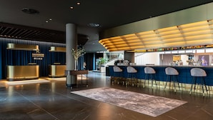 A modern lobby with a reception desk, bar area, and seating. - Radisson Collection Grand Place Brussels (Brussels)