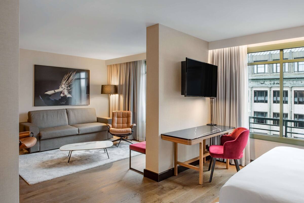 Une chambre d’hôtel équipée d’un canapé, d’un fauteuil, d’un bureau et d’une télévision.