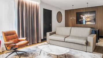 A modern living room with a leather armchair, a grey sofa, and a marble coffee table.