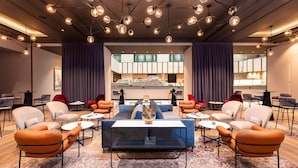 A modern lounge area with sofas, armchairs, and a coffee table, featuring a central decorative piece and overhead lighting. - Radisson Collection Grand Place Brussels (Brussels)