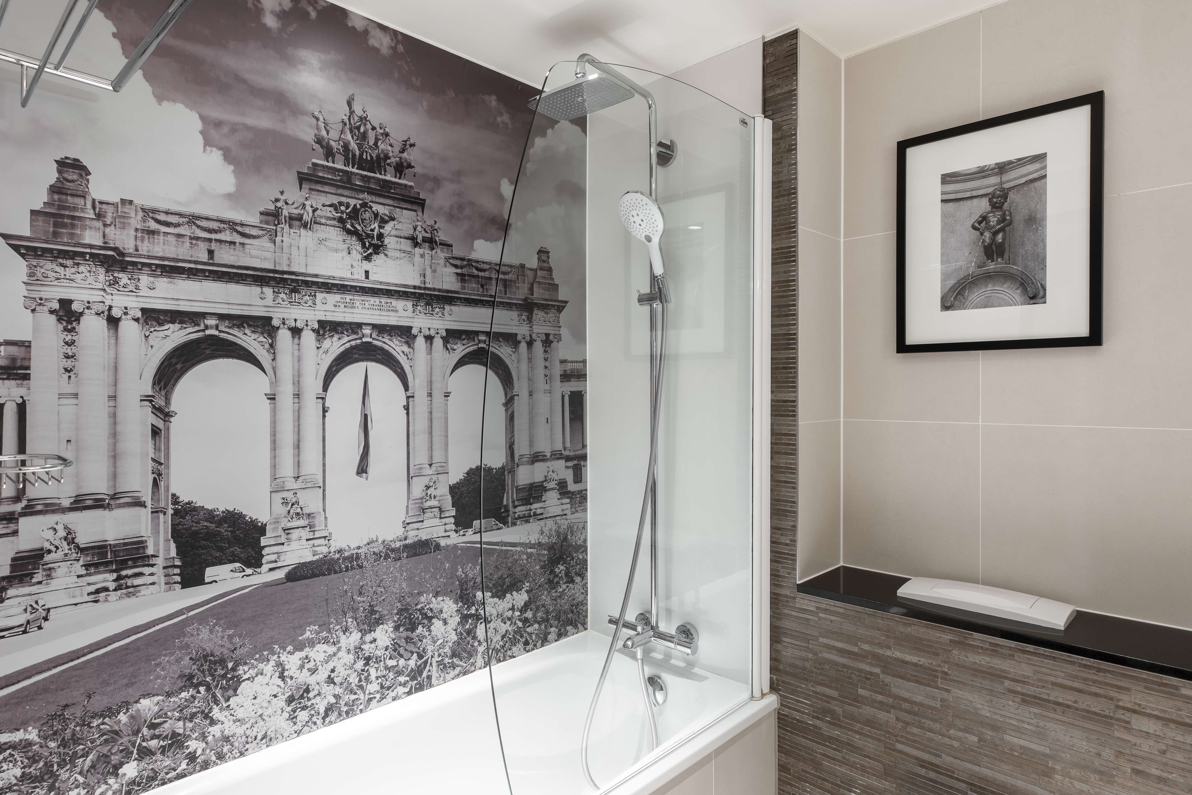 A bathroom with a glass-enclosed shower, a framed artwork on the wall, and a tiled floor.