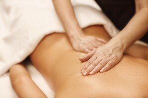 A close-up of hands performing a massage on a person's back.