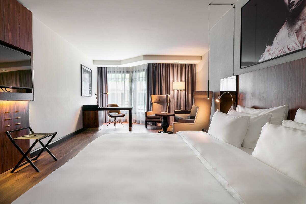 Une chambre d’hôtel avec un grand lit, un bureau, une chaise, une lampe et un téléviseur.