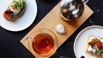 A breakfast setting with various dishes including eggs, bacon, toast, and pancakes, along with beverages and a teapot.