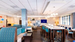 Rebedor d'hotel amb zones d'estar, una recepció i una pantalla gran que mostra el logotip de Hilton.