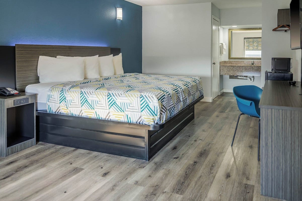 Una habitación de hotel moderna con una cama, una mesita de noche y un escritorio con una silla.