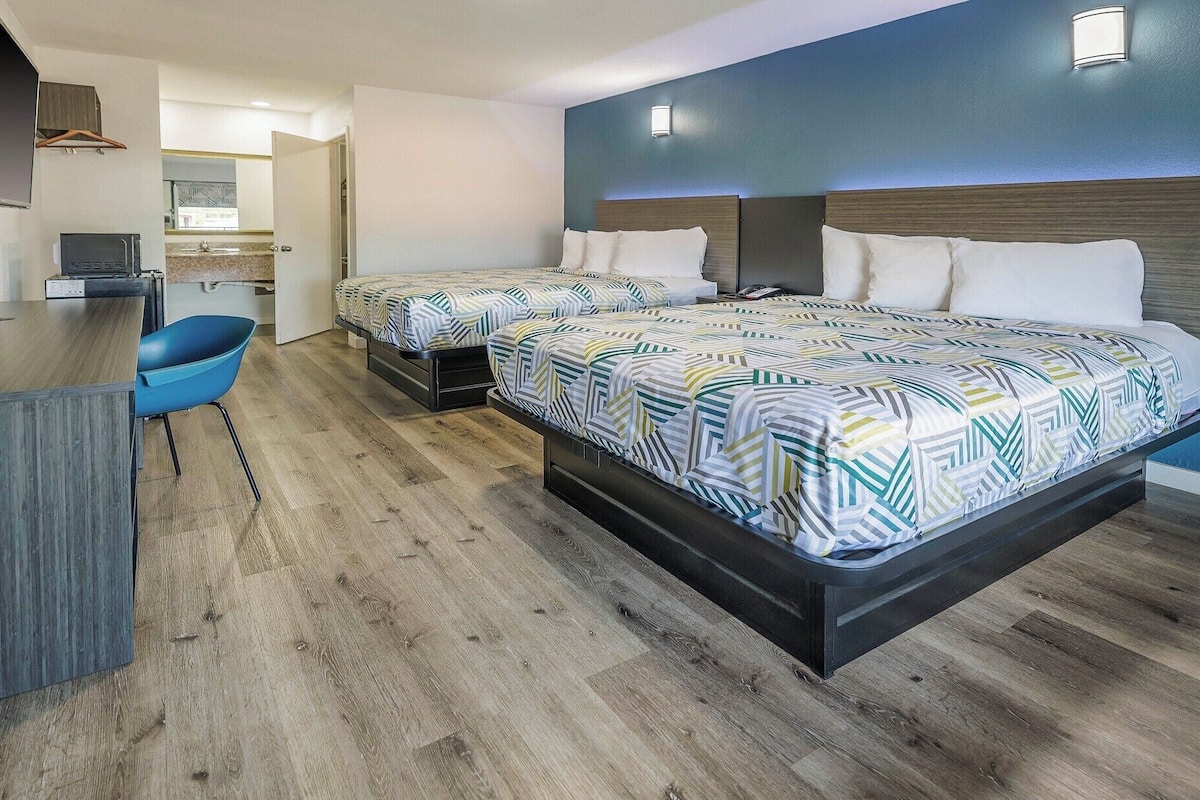 Habitación de hotel con dos camas, un escritorio y una silla.