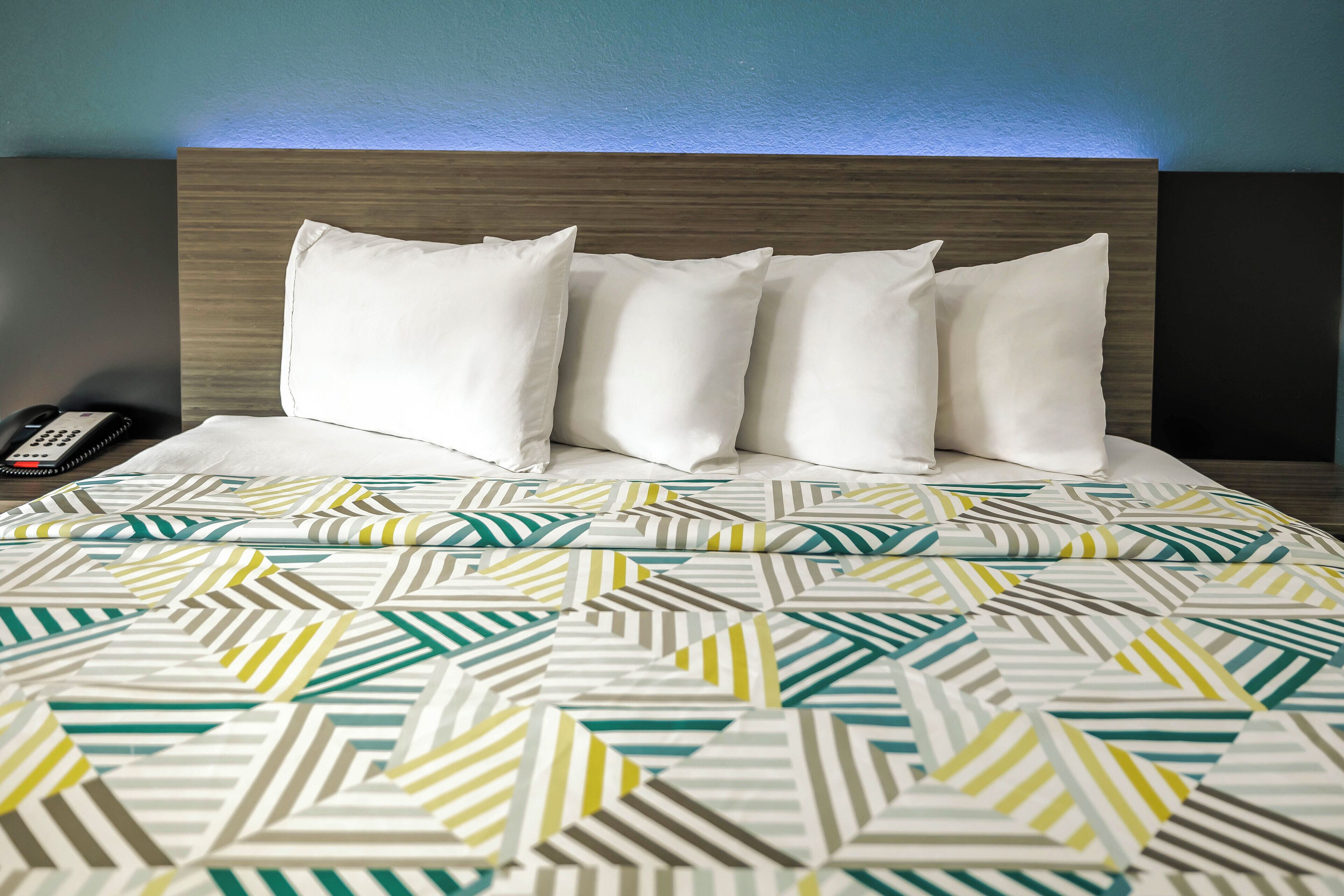 A hotel room with a bed, pillows, and a remote control.