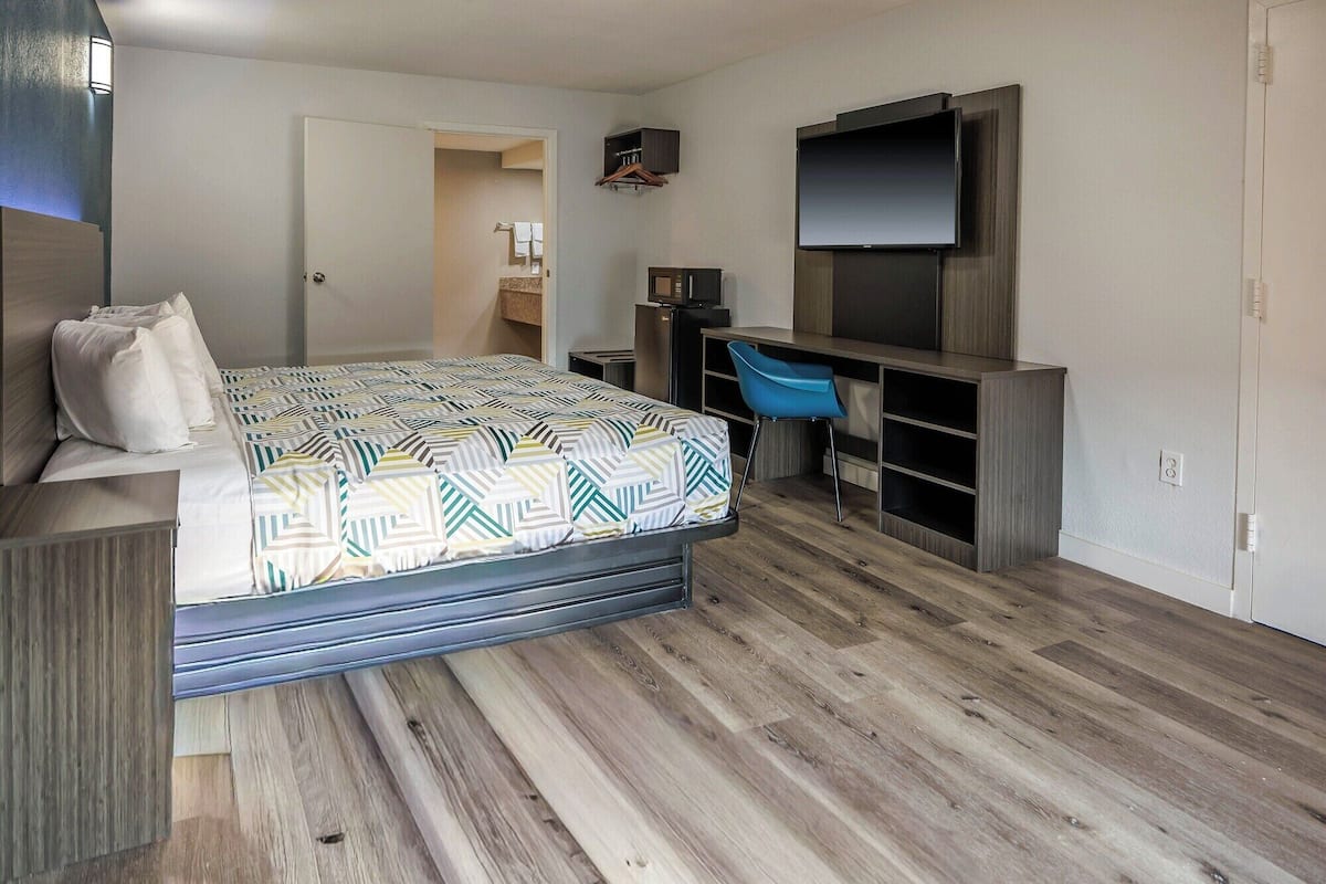 Un dormitorio pequeño con cama, televisión, escritorio y silla.