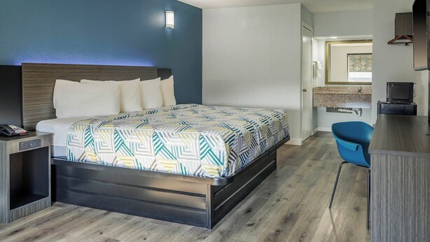 A modern hotel room with a bed, a desk, and a chair. - Motel 6 Greenwood, MS (Greenwood)