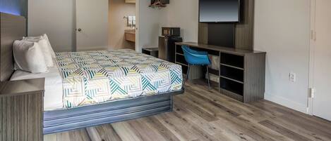 Un dormitorio con cama, escritorio, silla, televisor y armario.