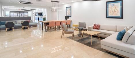 A modern interior with a dining area, sofas, and a kitchen in the background.