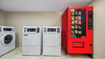 A laundry area with two front-loading washers and a red vending machine.