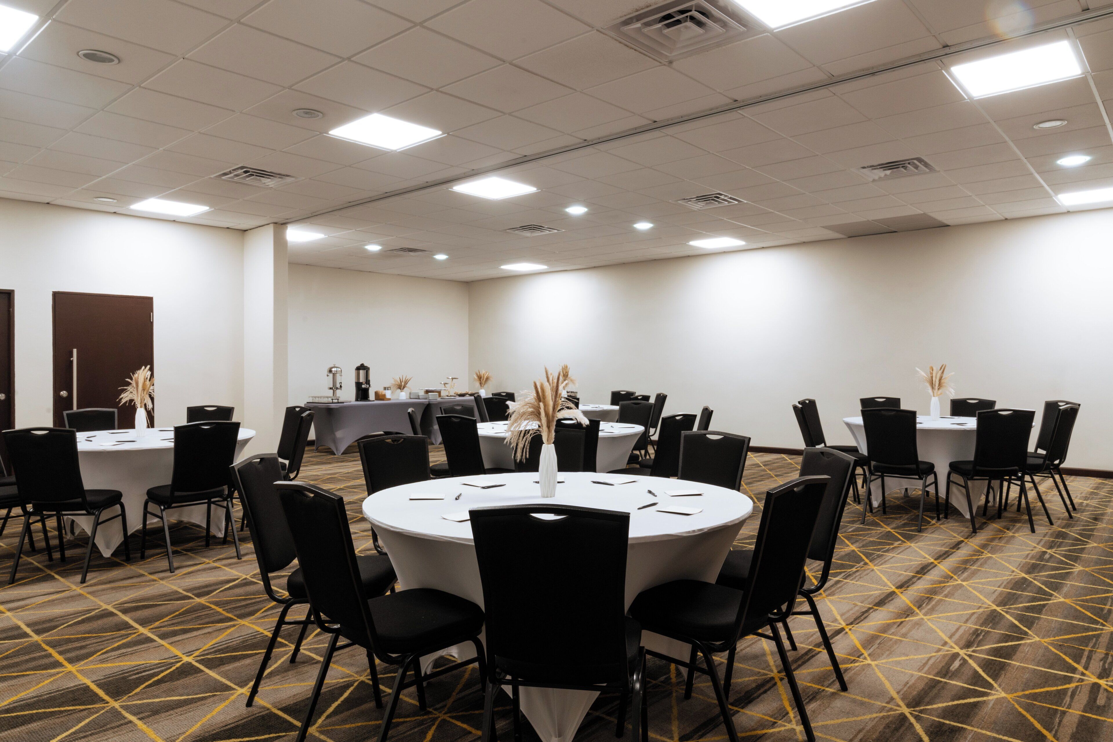 A conference room with multiple tables and chairs, arranged in a U-shape.