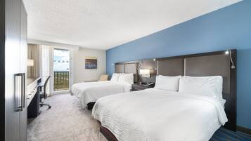 Habitación de hotel con dos camas, un escritorio, una silla y vistas al exterior.