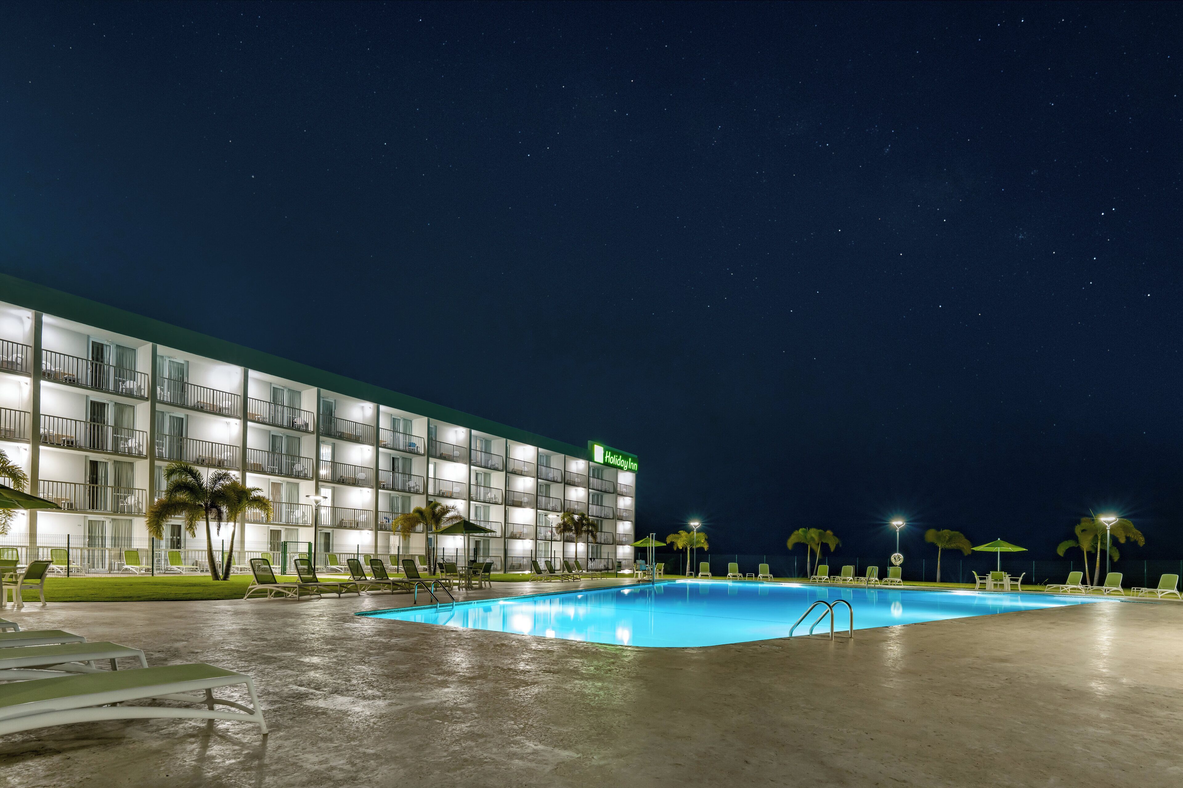 A Holiday Inn with a swimming pool, multiple balconies, and palm trees.