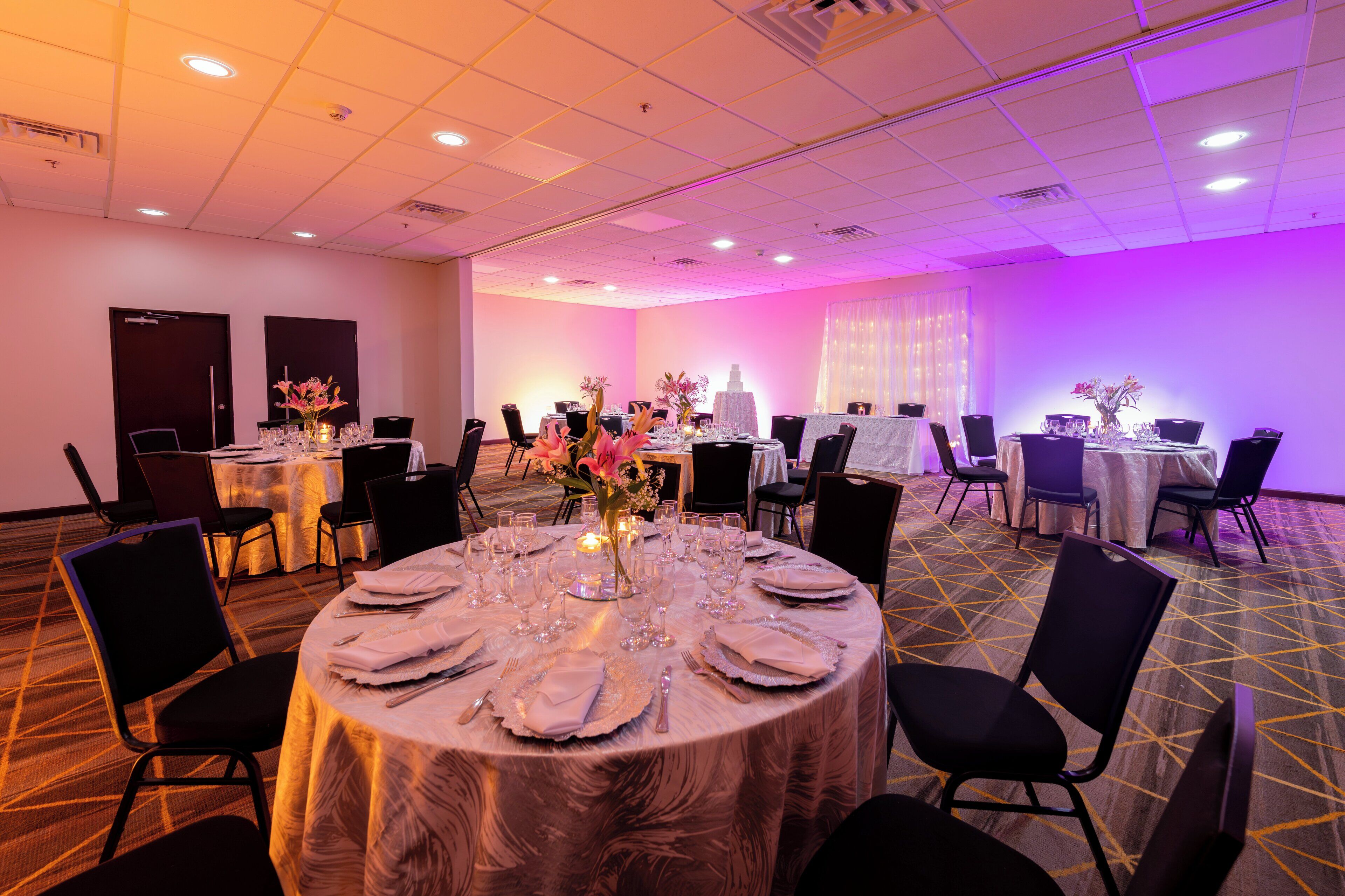 A conference room with multiple tables set for a meeting, equipped with chairs and tables, and a decorative centerpiece.