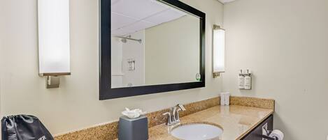 A hotel bathroom with a sink, mirror, towel dispenser, and a bag labeled 'H DRYER'.